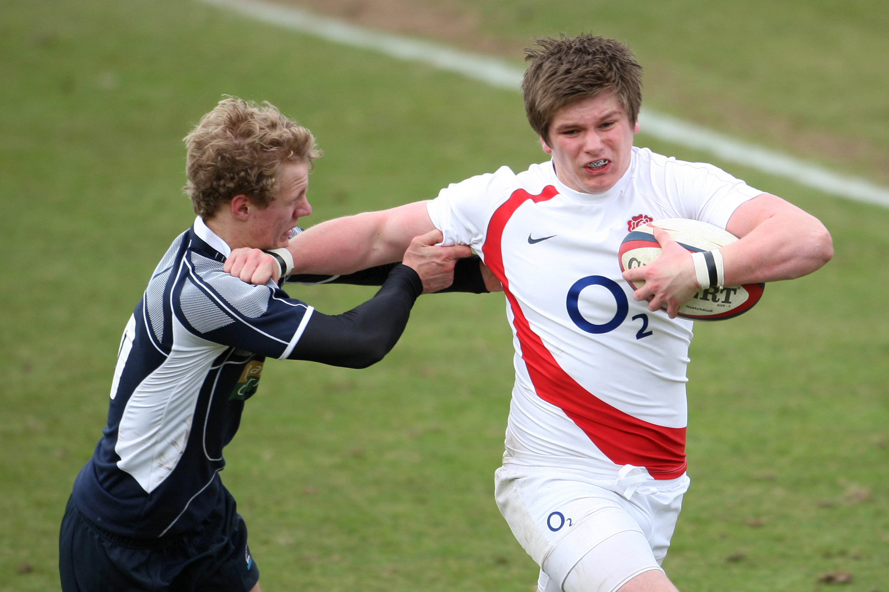 An England player with a rugby ball evading a Scotland player.