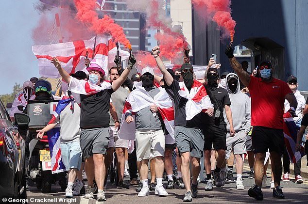 Masked protesters with flares demonstrate their opposition to the housing of asylum seekers in the Britannia International Hotel