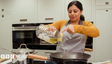 Assorted healthy vegetable oil bottle collection on wooden table in a old fashioned kitchen with low key illumination: Olive oil, hazelnut oil, almond oil, coconut oil and sesame oil