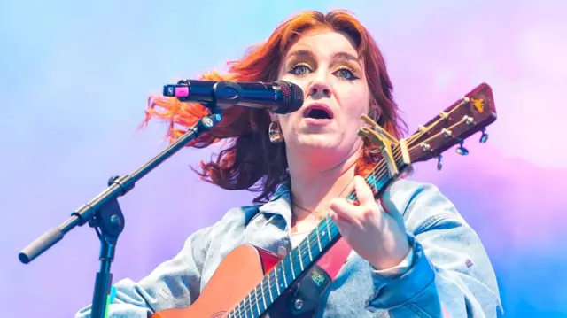 CMAT on stage playing guitar and singing