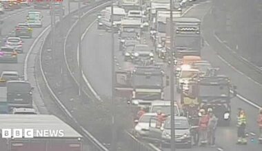 Emergency services seen on scene, with a number of vehicles which appear to have been in collision and traffic queuing behind