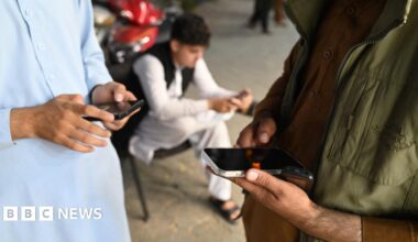 An Afghan man looks at his phone outside a convenience store