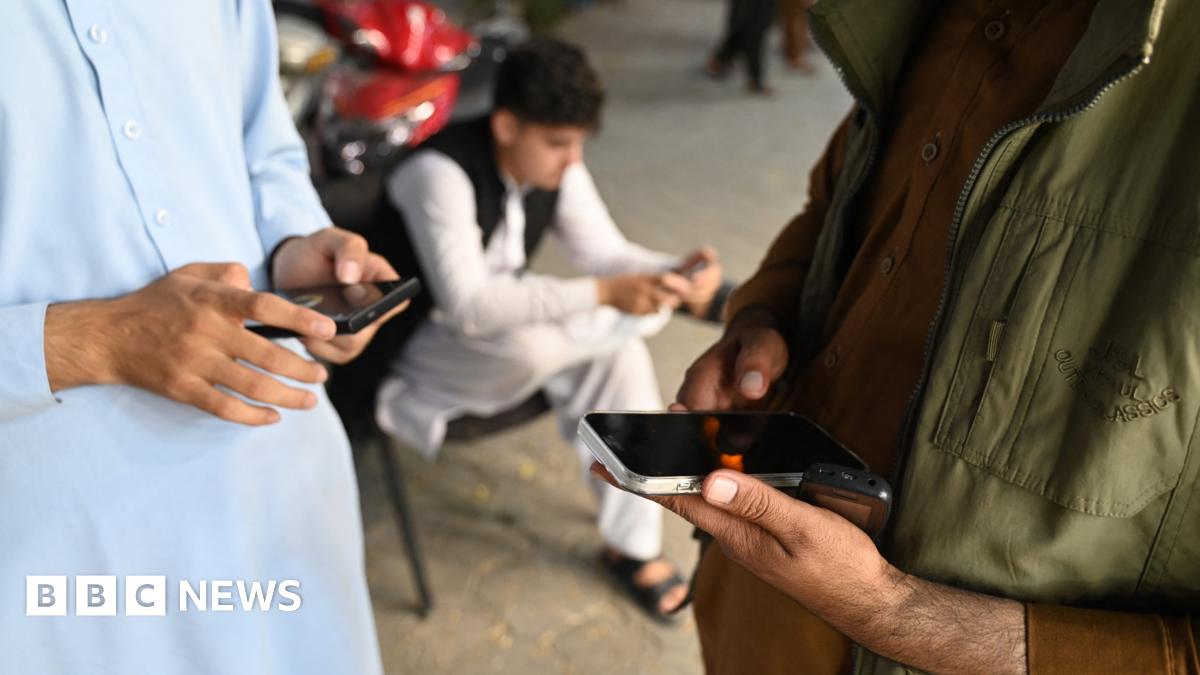 An Afghan man looks at his phone outside a convenience store