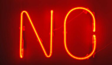 Red neon NO sign on a dark background. Sign says no in bright red narrow capital letters.