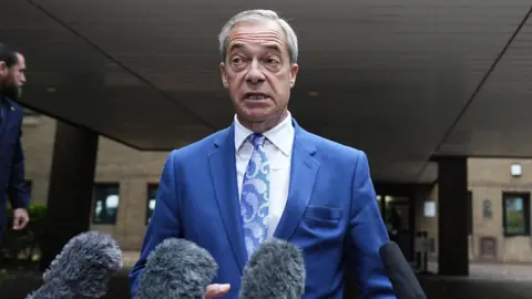 PA Media Nigel Farage on the court steps speaking to the gathered press. He has microphones in front of him and is wearing a blue suit jacket, blue and silver tie and a white shirt.