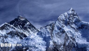 Mount Everest. Two mountain peaks covered in snow. The sky is dark blue and it looks stormy.