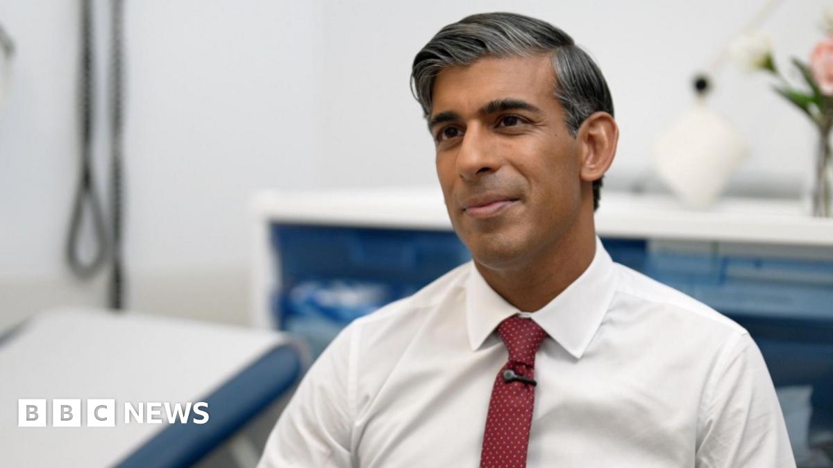 Mr Sunak sits in a hospital chair, wearing a white shirt and burgundy tie.