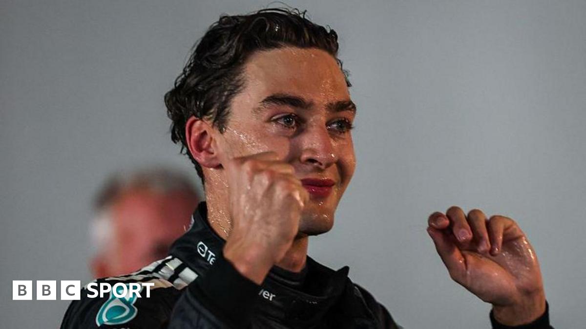 A champagne-covered George Russell lifts his arms in celebration after winning the Singapore Grand Prix