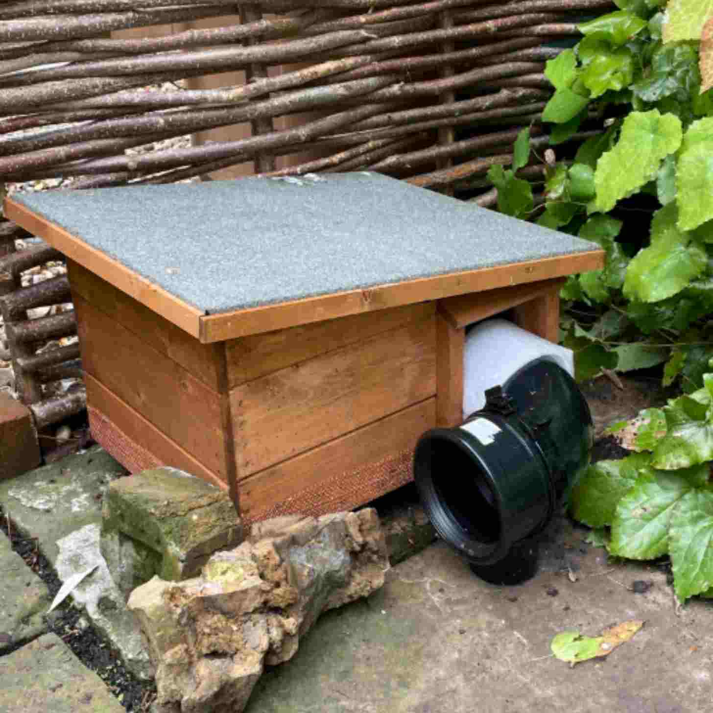 a hut in a backyard to a hole in a fence, led by a tube