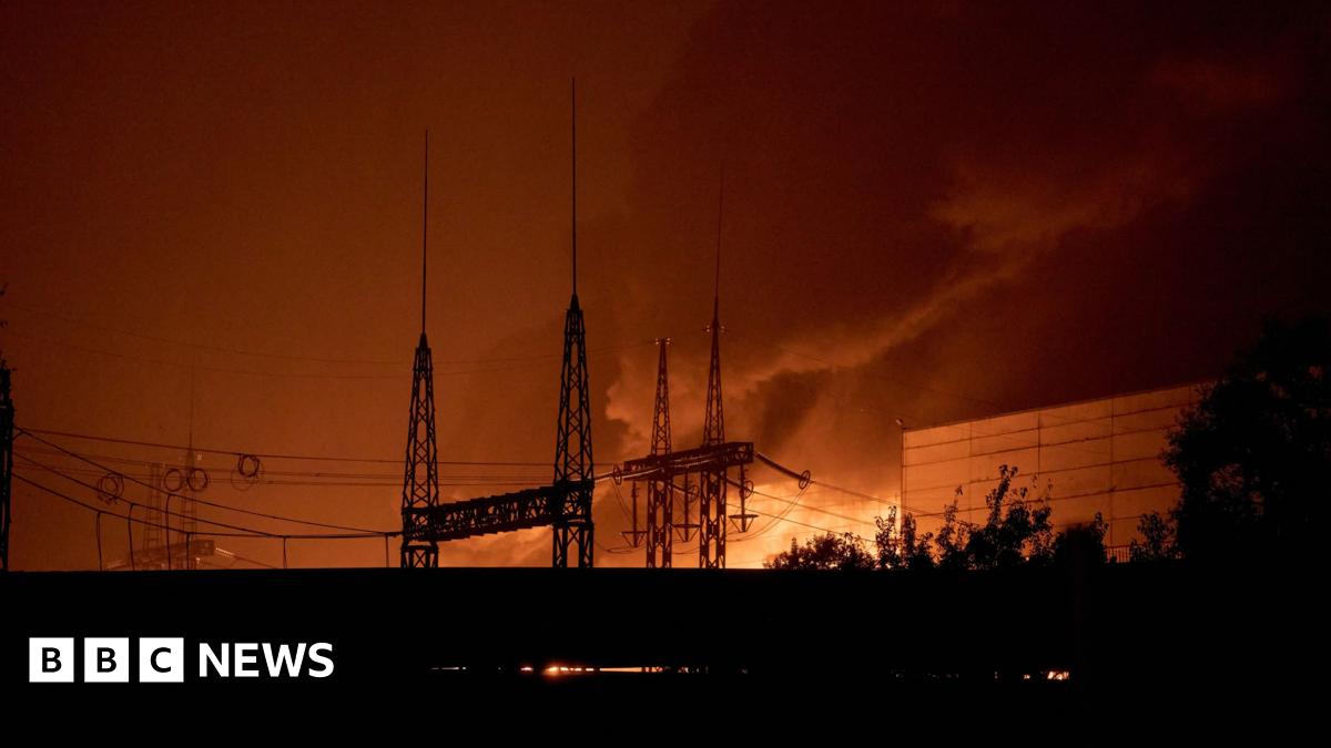 A long shot of a power lines in front of a bright orange blaze