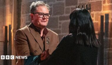 Claudia Winkleman sitting in an armchair in the Traitors castle in Scotland