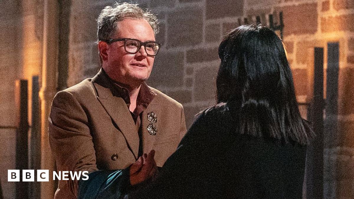 Claudia Winkleman sitting in an armchair in the Traitors castle in Scotland