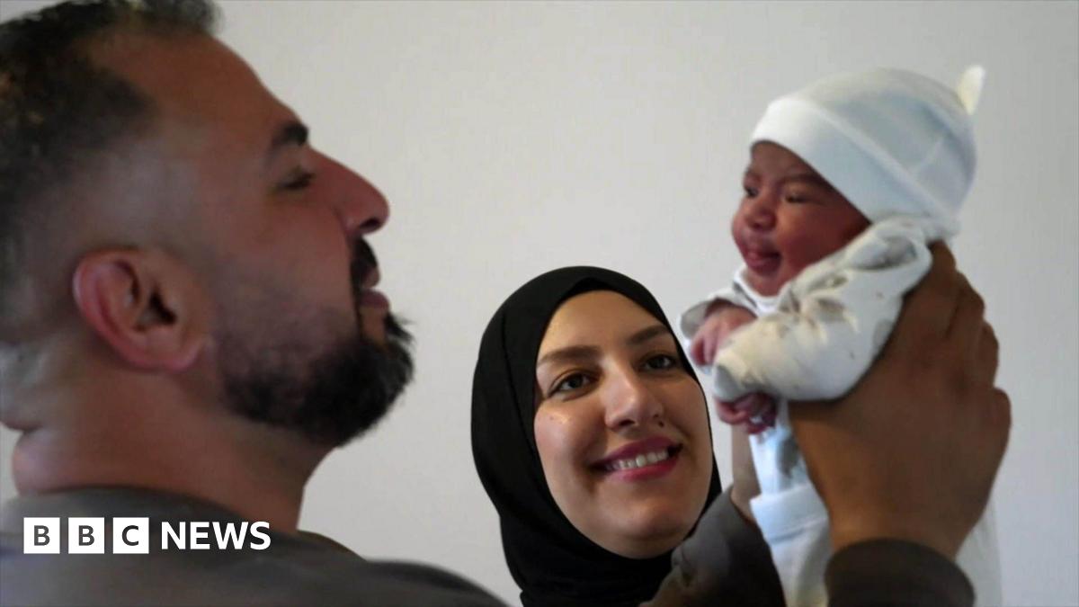 Ahmed with his wife, Nour and teenage daughter, Rahaf. They are all happy and focused on a sleeping newborn baby, being held by Ahmed and wrapped in a cream coloured blanket.