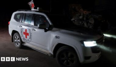 A white Red Cross jeep with the emblem of a red cross and the organisation's name on the side.