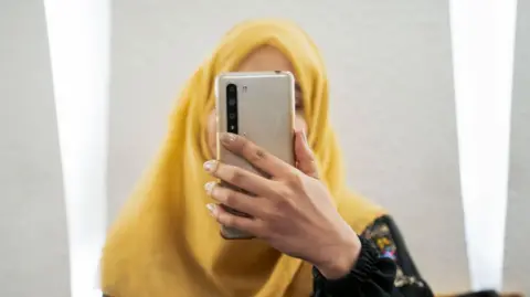 Getty Images File photo of a woman holding a phone