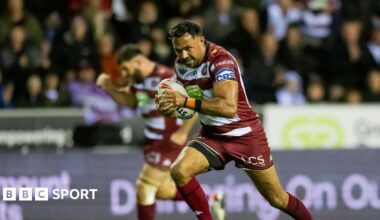 Wigan half-back Bevan French runs towards the try line as teammate Abbas Miski clenches his fist in celebration in the background.