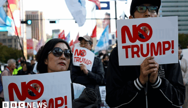 A man and a woman hold up slogans that read 'No Trump'.