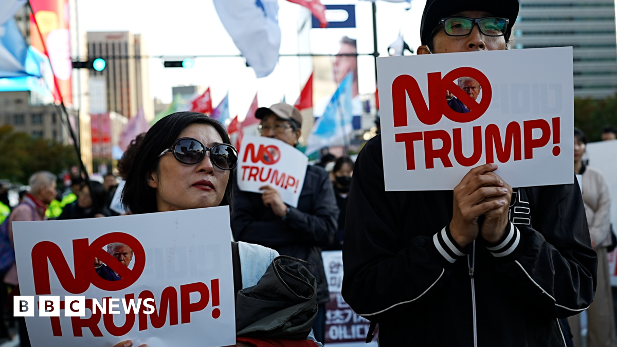 A man and a woman hold up slogans that read 'No Trump'.