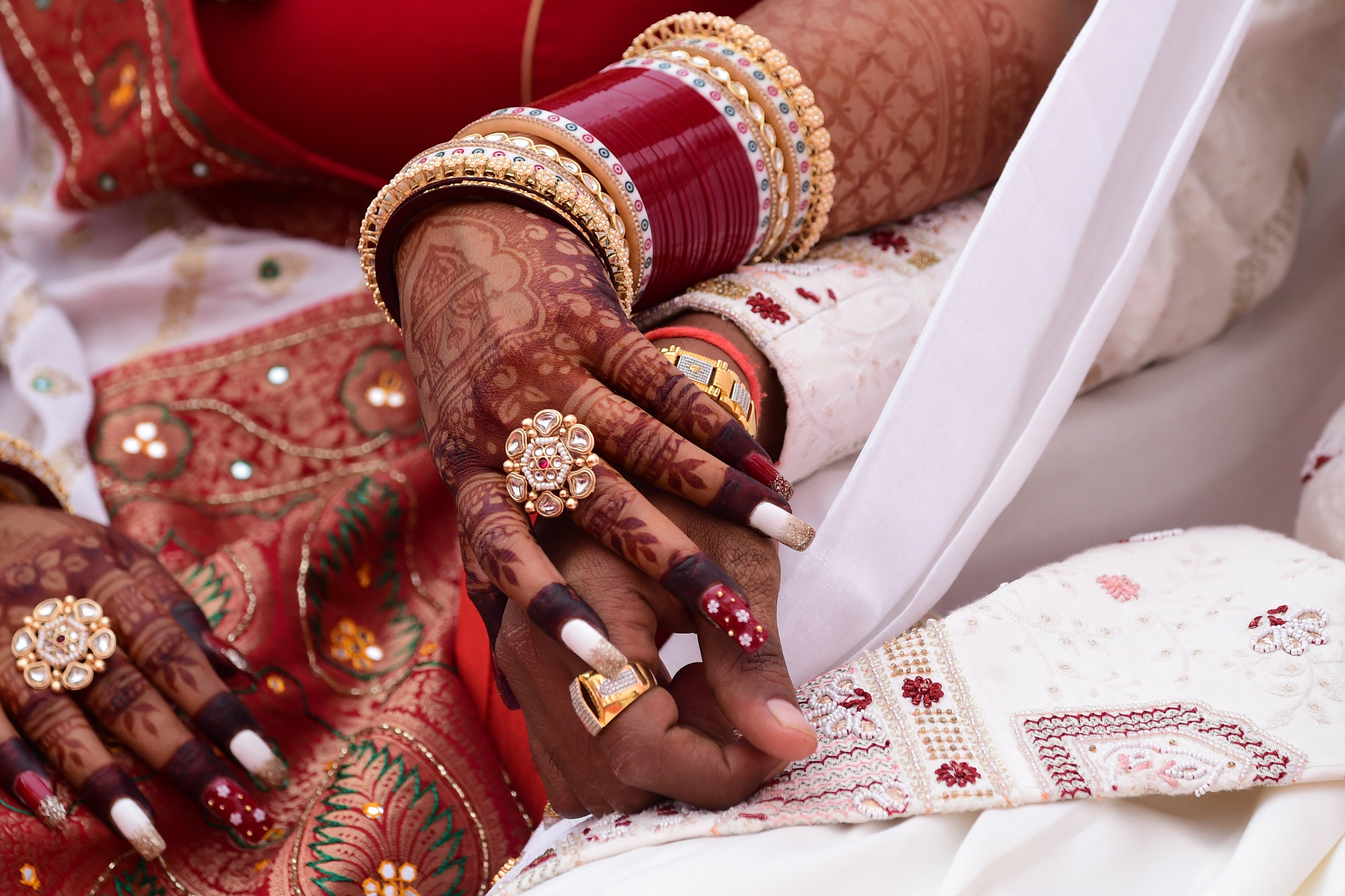 A bride holds her groom’s hand as they take part in a Hindu wedding ritual