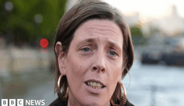 Headshot of Home Office Minister Jess Phillips. She has her short, light brown hair tucked behind her ears. She wears a thick black, jacket and very large gold hoop earrings.