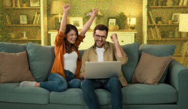 Young couple looking excited whilst sitting on sofa with a laptop.