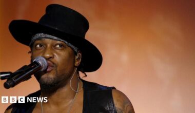 D'Angelo singing into a microphone on stage.