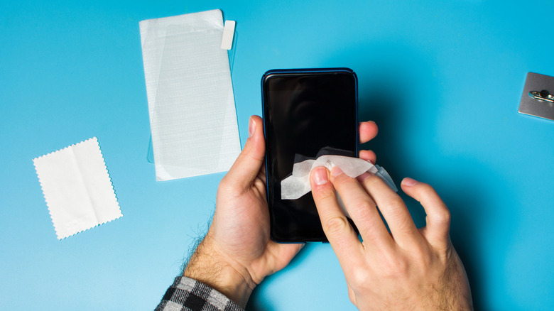 A pair of hands cleaning a smartphone screen