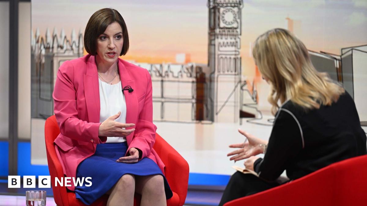 A large crowd of protesters holding Palestinian flags and placards are gathered with the Houses of Parliament in the background.