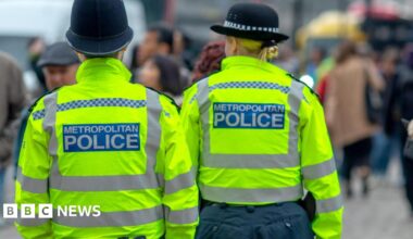 Two police officers are wearing yellow jackets with black hats