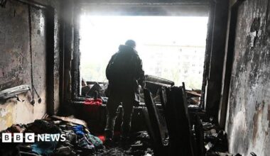 A person stands amid burnt debris in an apartment damaged by a Russian drone strike on October 10, 2025 in Kyiv, Ukraine