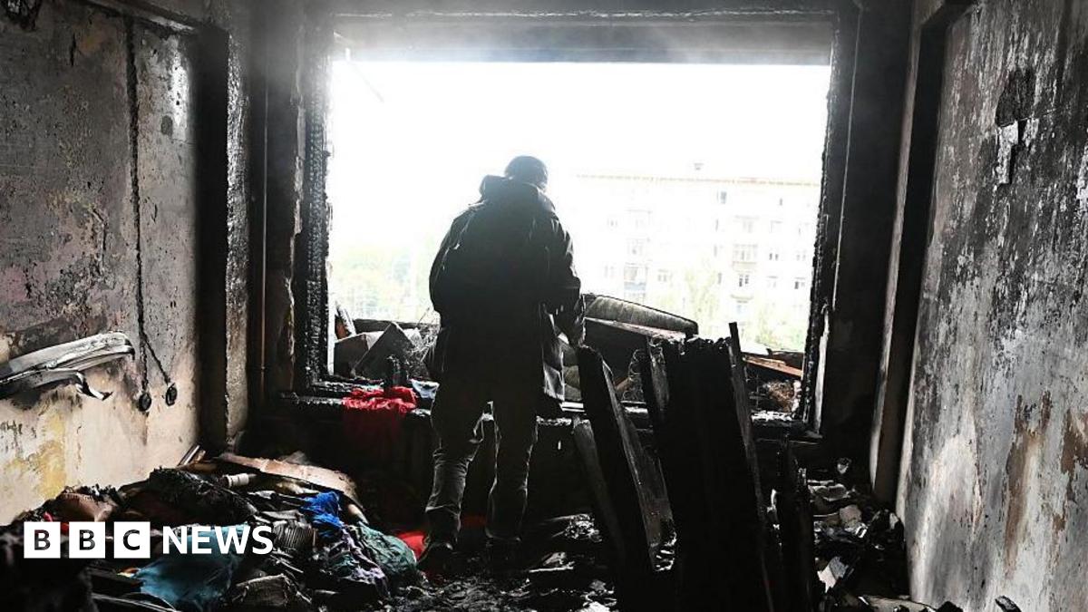 A person stands amid burnt debris in an apartment damaged by a Russian drone strike on October 10, 2025 in Kyiv, Ukraine