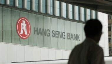 Hang Seng Bank logo on the company's headquarters, with a person silhouetted in the foreground