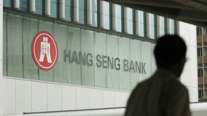 Hang Seng Bank logo on the company's headquarters, with a person silhouetted in the foreground
