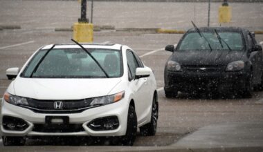 Cars parked in a lot during snowfall with their windshield wipers raised at Raleigh-Durham International Airport