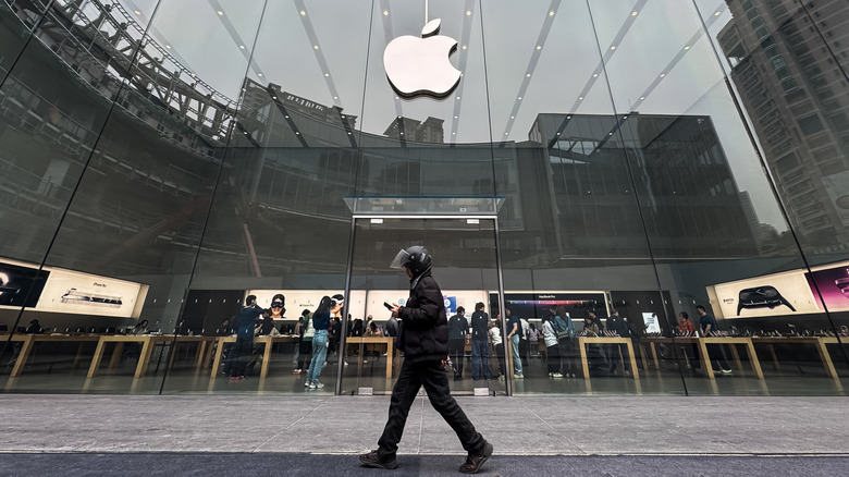 A person walking in front of an Apple store.