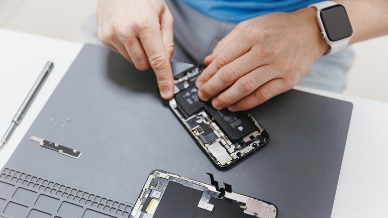 Technician replacing smartphone battery on a mat