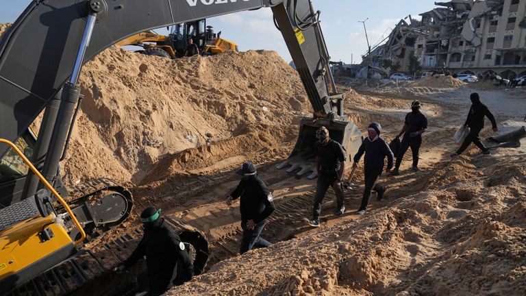 Hamas members and Egyptian workers search for the bodies of hostages in the southern Gaza Strip on Tuesday. Pic: AP