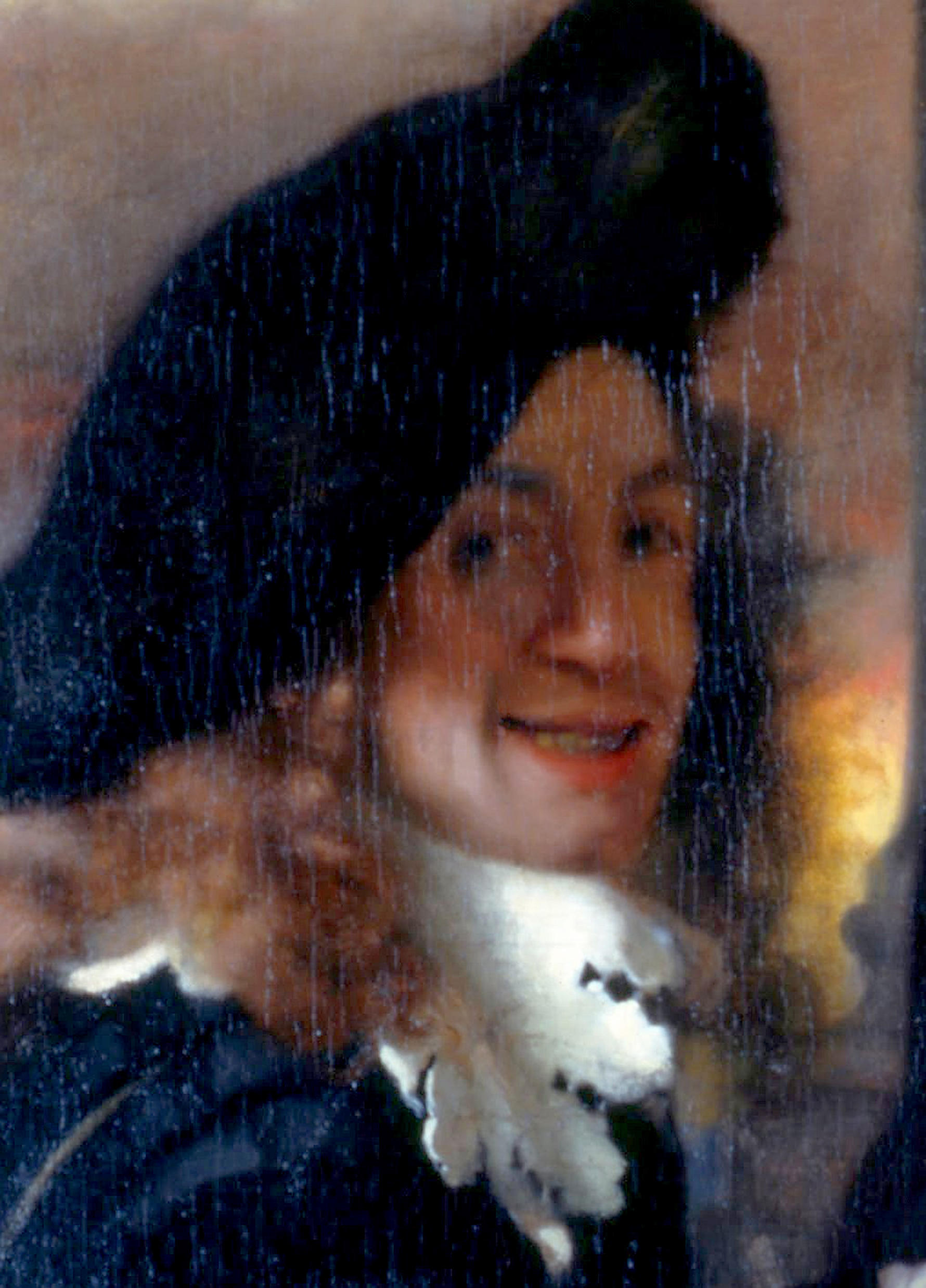 Painting of Johannes Vermeer, wearing a black cap, a white ruffled collar, and brown hair covering his ears, smiling.