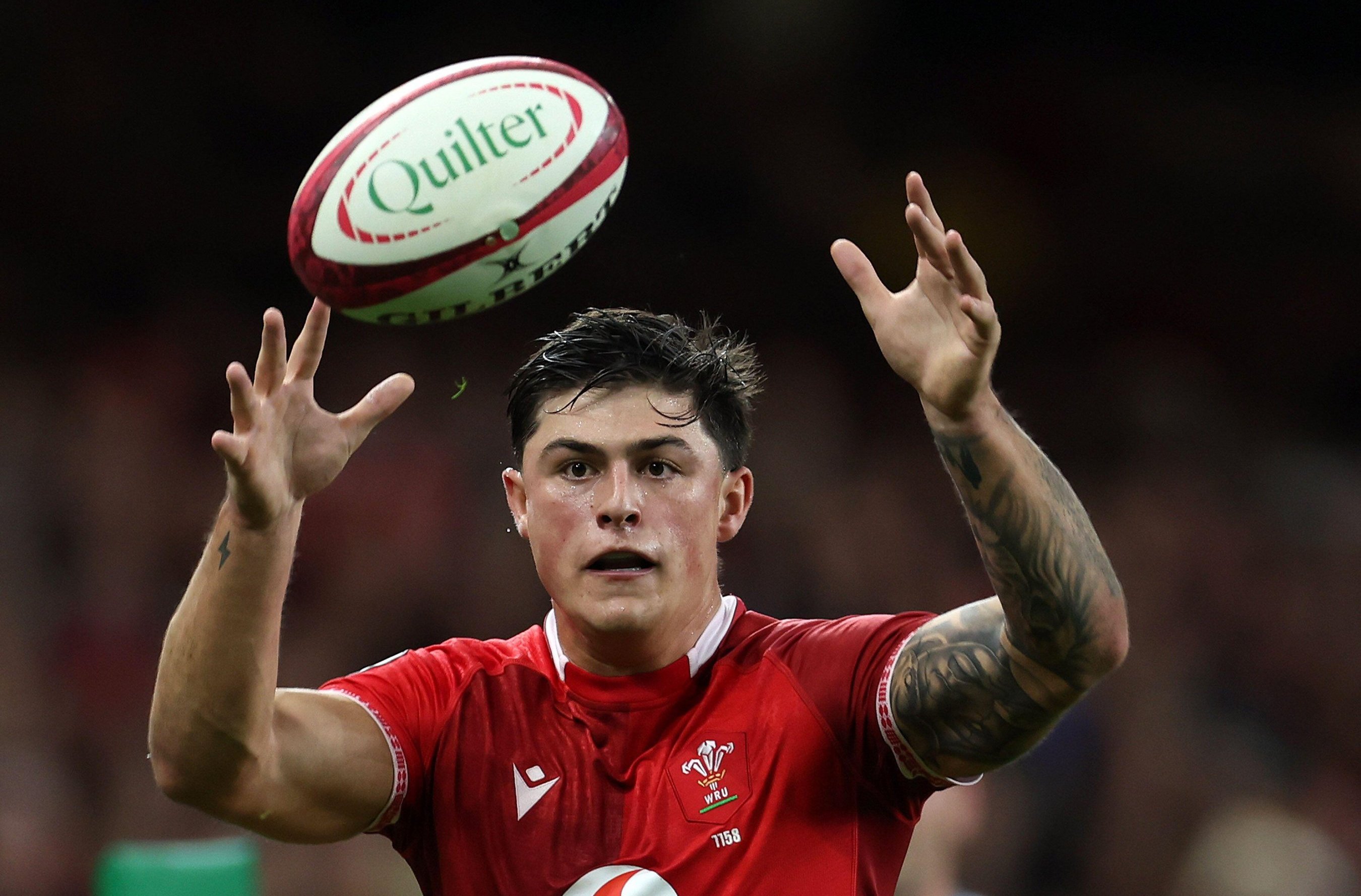 Louis Rees-Zammit of Wales reaching for a rugby ball during a match.
