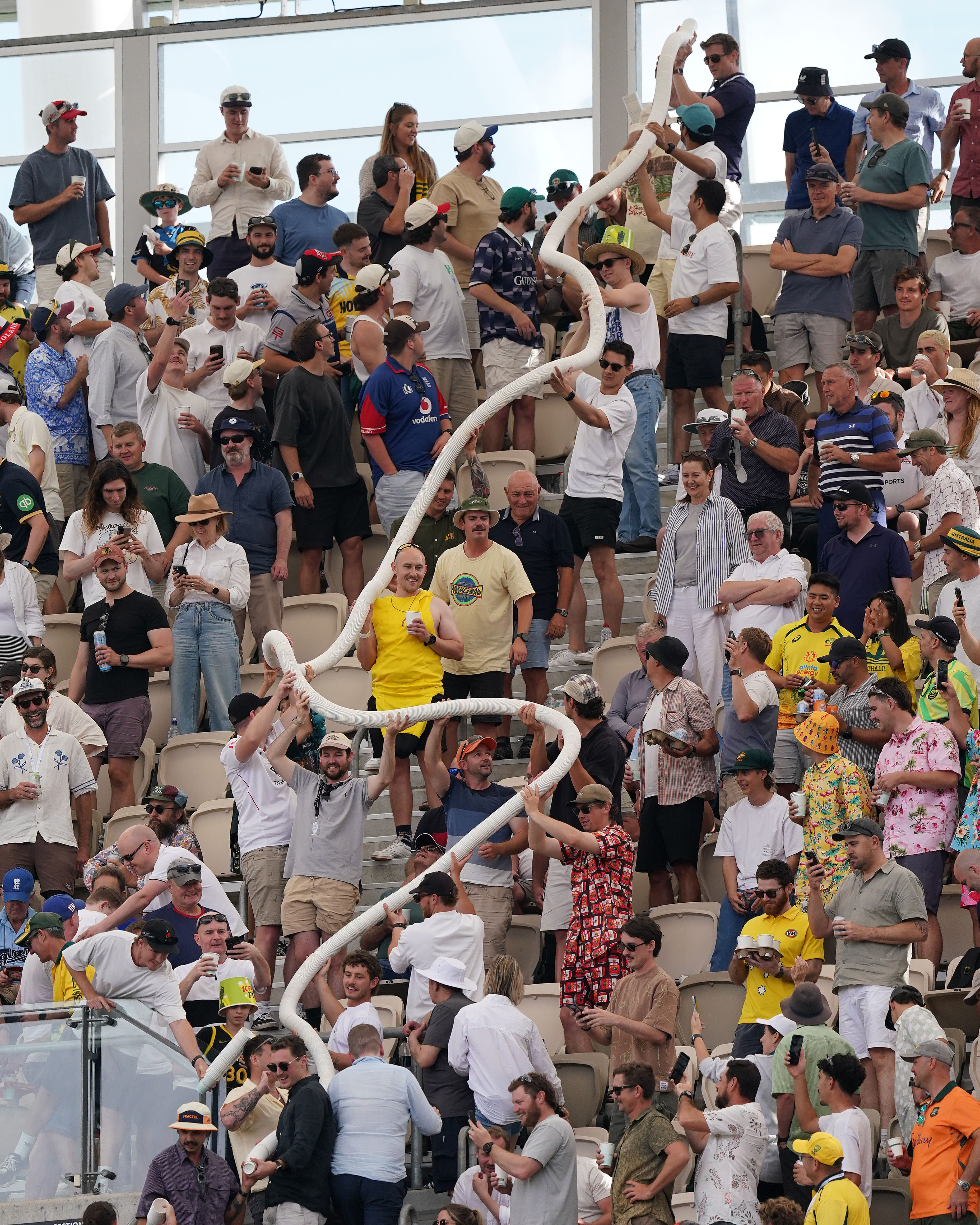 Fans at Optus Stadium in Perth pass a beer snake made of plastic cups through the stands.