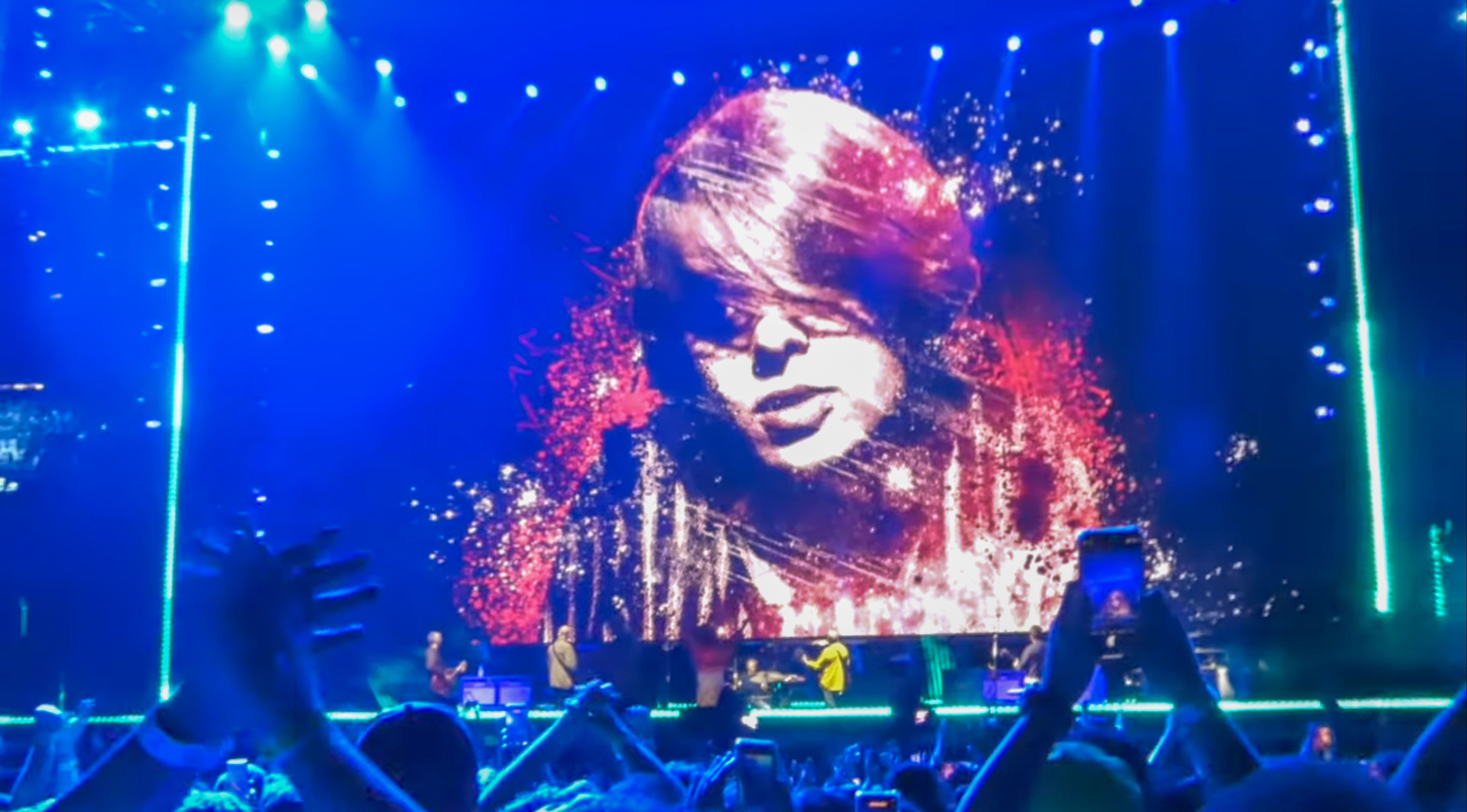 Oasis concert in Brazil shows a tribute image of Gary “Mani” Mounfield on a large screen.