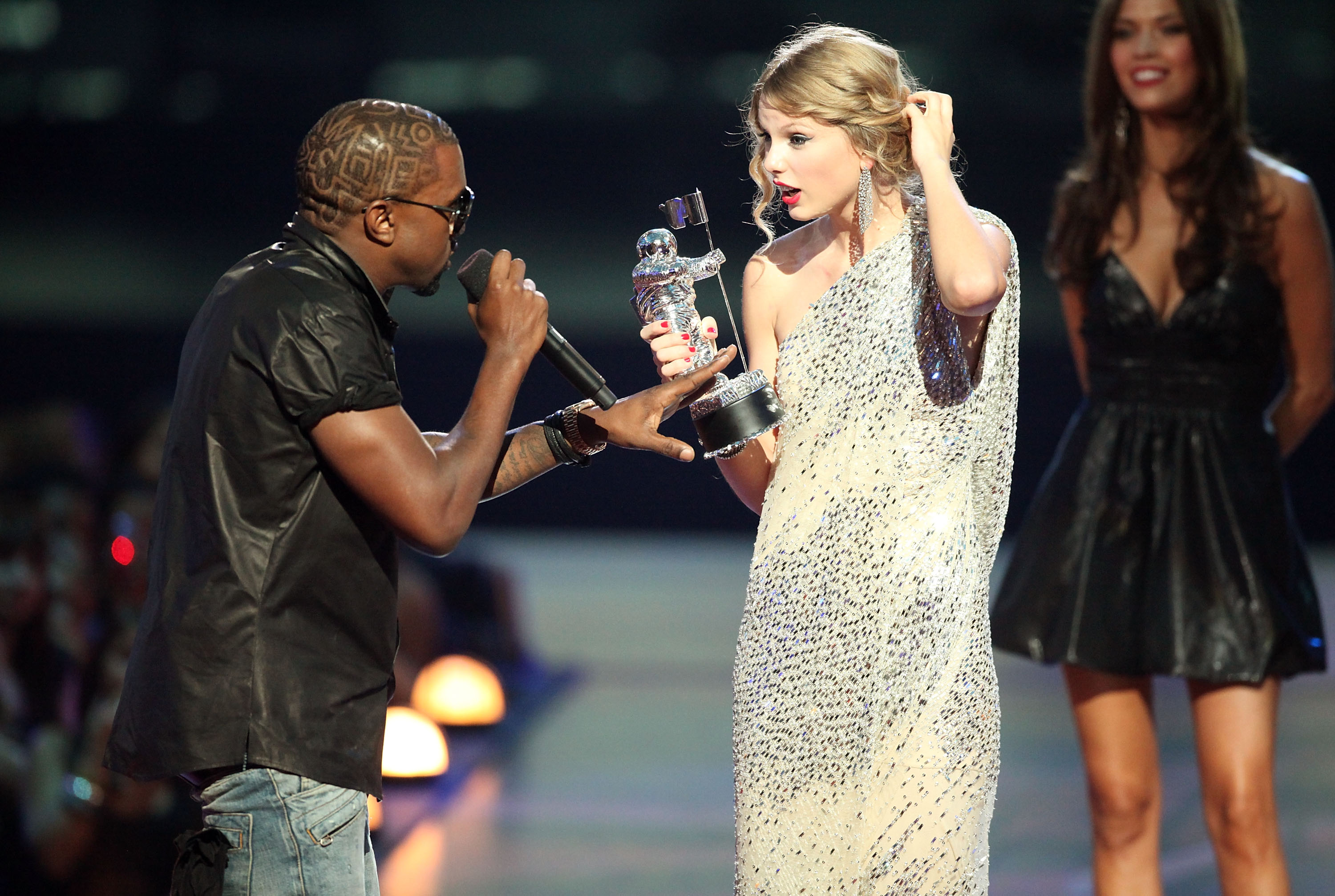 Kanye West takes the microphone from Taylor Swift who holds her "Best Female Video" award at the 2009 MTV Video Music Awards.