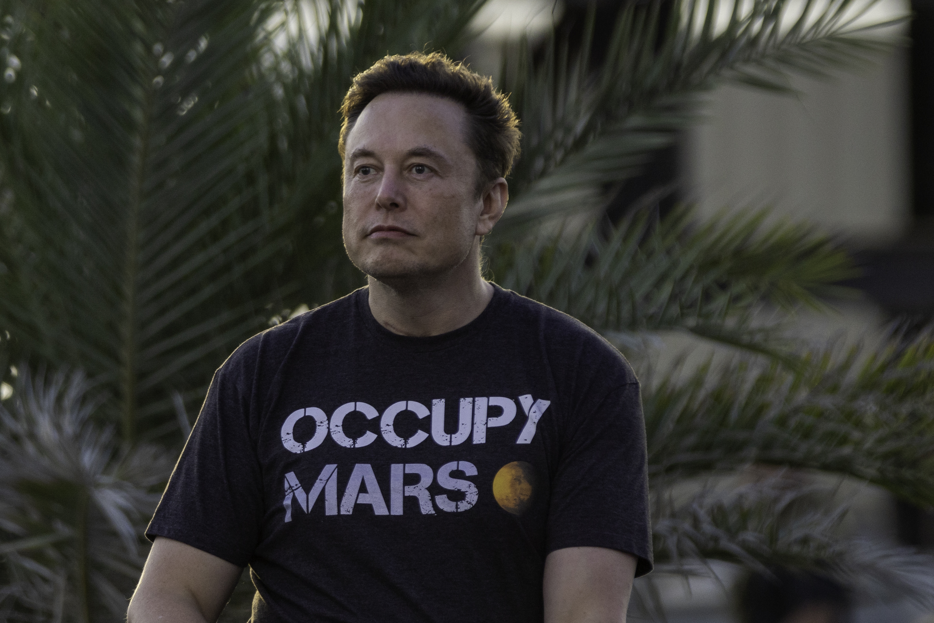 Elon Musk in a black "Occupy Mars" t-shirt.