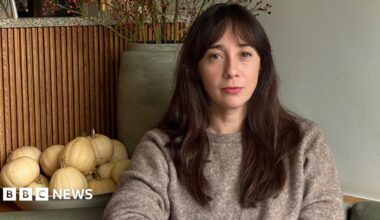 A woman with long dark brown hair looks sadly at the camera