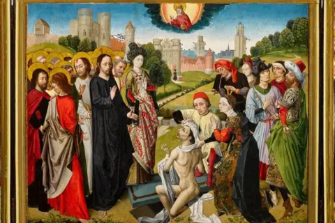 Sotheby's Close-up of the central image of the triptych depicting Jesus and his apostles with gold halos on their heads on the left. Jesus is holding up his hand to a naked man on the ground. Watching, on the right of the picture, is another group of people dressed in fine medieval clothes. In the background is a large castle. In the sky is a sun and at the centre is a bearded man in red robes with a large gold halo.