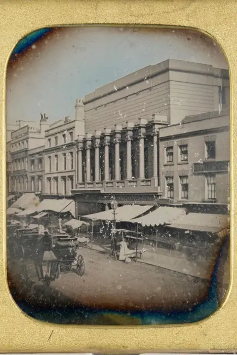 Private Collection A black and white image of New Street captured on a daguerreotype, it shows shop frontages with canopies as well as horses and carts