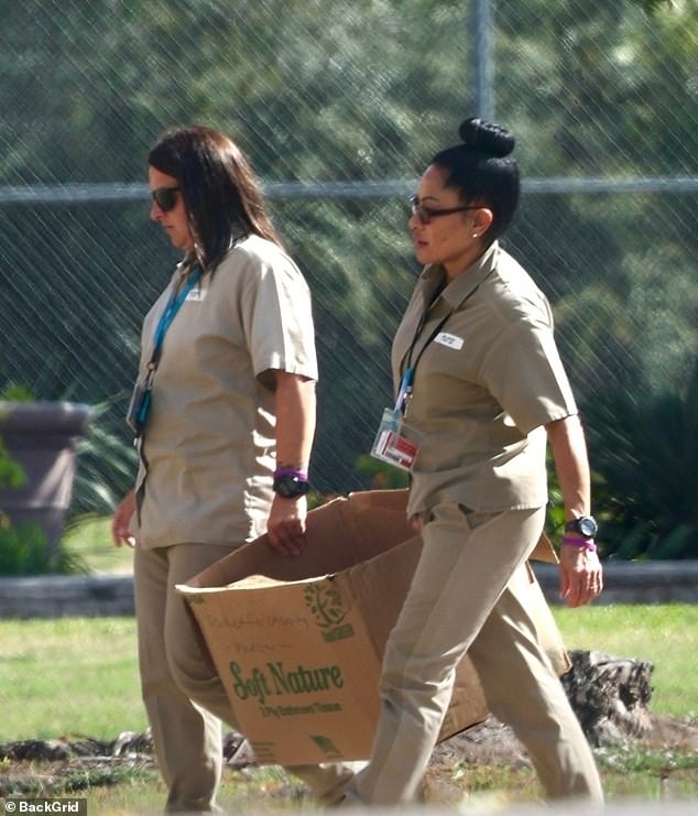 The convicted fraudster, 52, was pictured hauling a cardboard box of garbage with another inmate inside the Texas federal prison camp where she's currently serving time