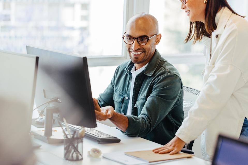 Software engineers using a computer and having a discussion in an office