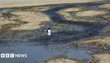 A woman stands by an almost entirely dried out river in Tehran that was once full