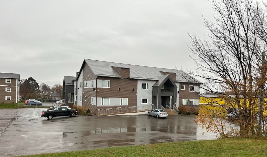 A two-storey apartment building surrounded by a parking lot